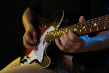 Siyah arka planda gitar çalan adam, ele odaklan.