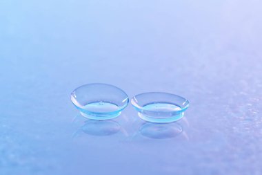 Kontakt lensler ve su damlaları mavi ayna yüzeyine, yakın plan.