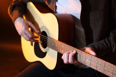 Kahverengi arka planda gitar çalan adam, yakın plan.
