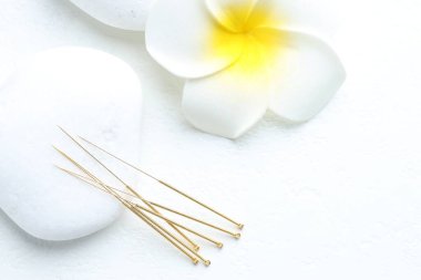 Akupunktur iğneleri, spa taşları ve çiçek beyaz arka planda, düz yatıyordu.