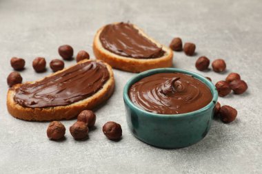 Çikolatalı fındıklı tostlar ve fındıklar gri masada, yakın plan.