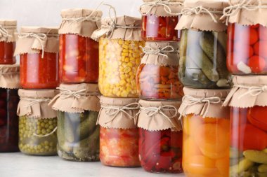 Işık masasında farklı turşu ürünleri olan bir sürü kavanoz.