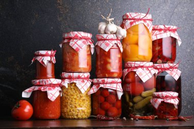 Pek çok kavanoz farklı turşu ürünleri ve malzemeler ahşap masada.