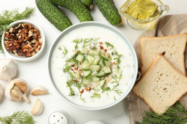Salatalık çorbası ve kabın içinde fındık, beyaz masada ürünlerin arasında, düz yerde.
