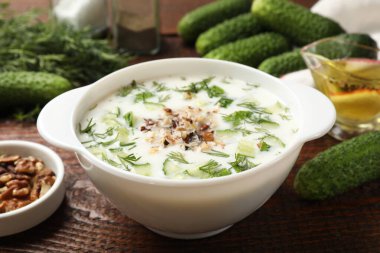 Taze lezzetli salatalık çorbası ve ahşap masa malzemeleri, yakın plan.