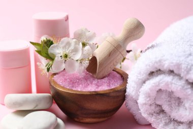 Kozmetik ürünleriyle spa kompozisyonu, çakıl taşları ve pembe arka planda güzel çiçekler, yakın plan.