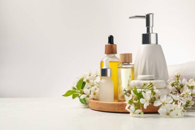 Spa ürünleri, çakıl taşları ve beyaz masadaki güzel çiçekli dallar, yakın plan. Metin için boşluk