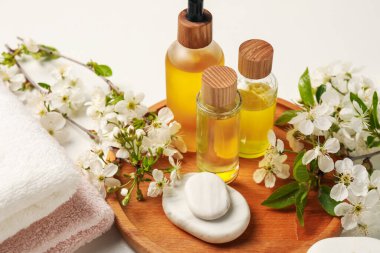 Spa ürünleri, çakıl taşları ve beyaz masadaki güzel çiçekli dallar, yakın plan.