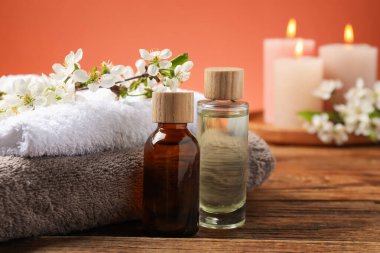 Kozmetik ürünleri, güzel çiçekler, ahşap masada yanan mumlar, seçici odak