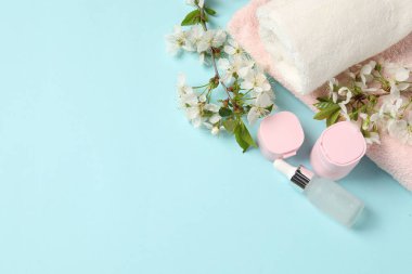 Kozmetik ürünleri, havlular ve açık mavi arka planda güzel çiçekli spa kompozisyonu. Metin için boşluk