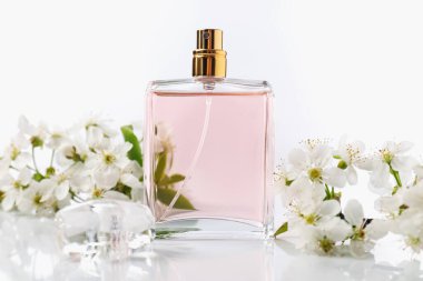 Aromatik parfüm ve beyaz arka planda güzel çiçekler, yakın plan.