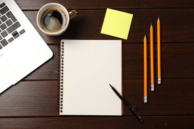 Defter, kalem, kalem, yapışkan not, sehpadaki kahve ve dizüstü bilgisayar, düz konum.