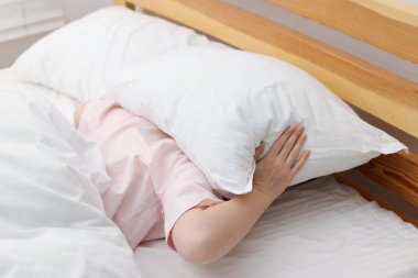 Kadın evinde yastıkla kendini örtüyor. Uykusuzluk sorunu