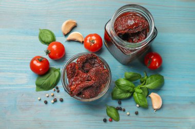 Lezzetli güneşte kurutulmuş domatesler, taze sebzeler, fesleğen ve sarımsak mavi ahşap masa, düz uzanmış