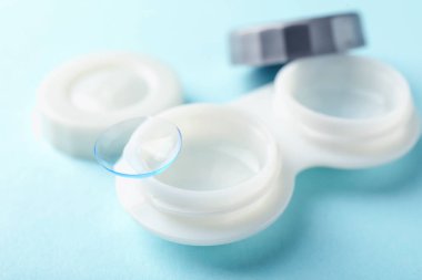 Açık mavi arkaplanda kontak lensler ve bavul, yakın plan