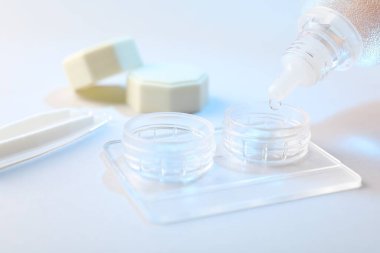 Işık arkaplanındaki kontakt lenslerle birlikte çözelti dosyaya damlıyor, yakın plan
