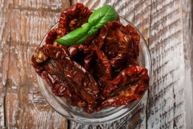 Lezzetli güneşte kurutulmuş fesleğenli domatesler ahşap masada, üst manzara