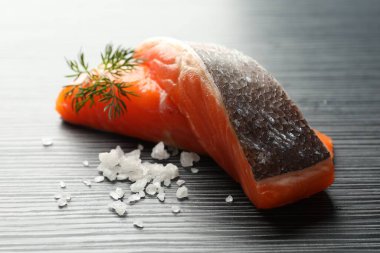 Deniz ürünleri. Somon fileto parçaları ve baharatlar siyah ahşap masada, yakın plan.