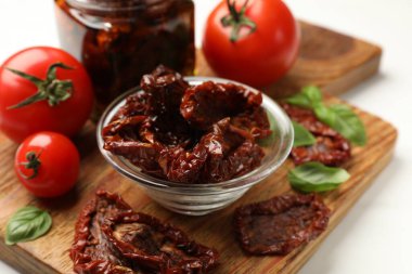 Lezzetli, kurutulmuş domatesler ve taze sebzeler beyaz masada, yakın plan.