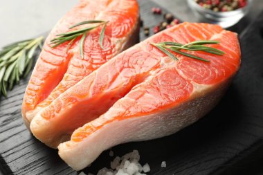 Deniz ürünleri. Çiğ somon bifteği, biberiye ve baharatlar gri masada, yakın plan.