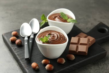 Lezzetli çikolata, parçalar, nane ve fındık. Gri desenli masa, yakın plan.