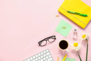 Pembe zemin üzerinde kırtasiye ve çiçeklerle düz kompozisyon, metin için boşluk