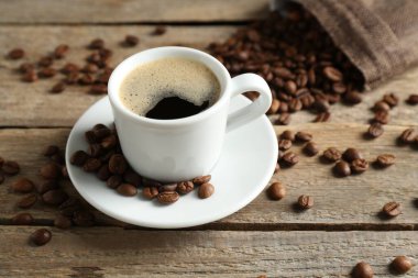 Aromatik kahve fincanda ve fasulyeler ahşap masada, yakın plan.