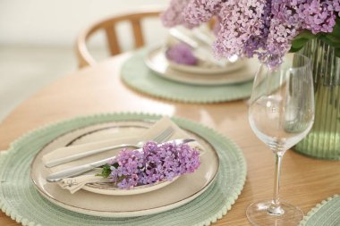 Güzel leylak çiçekleri, tabaklar, çatal bıçak takımı ve cam, kapalı masa, yakın plan.