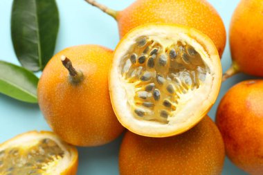 Olgun sarı tutku meyveleri ve açık mavi arka planda yapraklar, yakın plan.