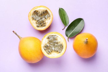 Olgun sarı çarkıfelek meyveleri ve yaprakları leylak arka planda, düz yatıyordu.