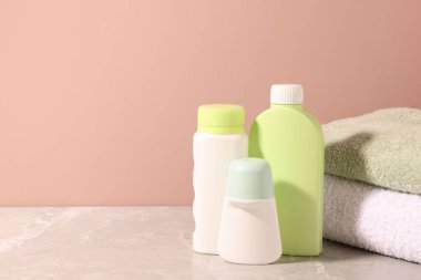 Açık kahverengi duvarın yanındaki gri masada farklı banyo ürünleri. Metin için boşluk