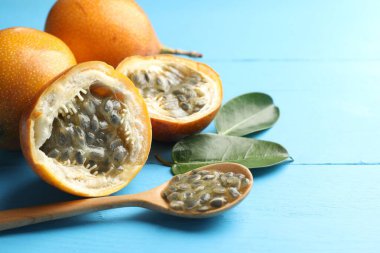 Olgun tutku meyveleri, yeşil yapraklar ve tohumlar açık mavi ahşap masada, yakın plan. Metin için boşluk