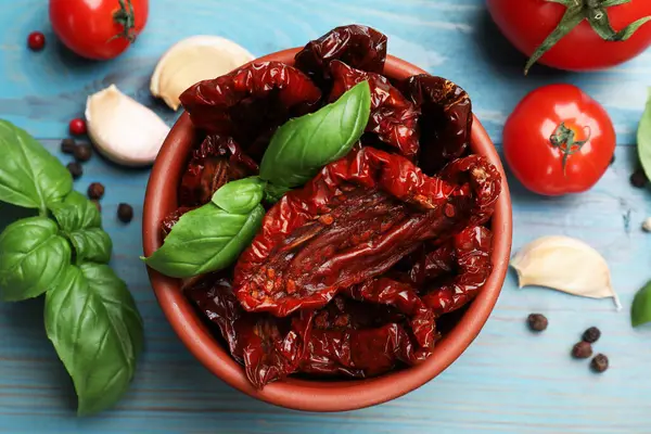 Lezzetli güneş, kasede kurutulmuş domatesler, taze sebzeler ve baharatlar açık mavi ahşap masa, düz yatıyordu.