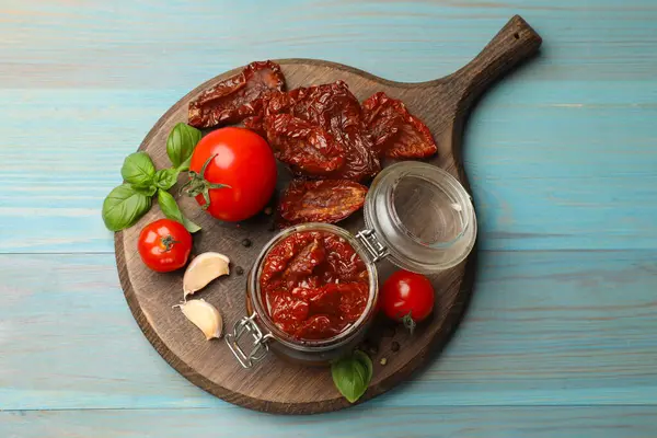 Lezzetli, kurutulmuş domatesler, taze sebzeler ve açık mavi ahşap masa üzerinde biberler.