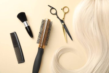 Saç tokası ve bej arka planda farklı kuaför aletleri.