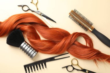 Saç kilitleri ve bej arka planda farklı kuaför aletleri, düz yatış