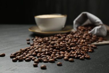 Kahve çekirdekleri ve sıcak içecek siyah masada, yakın plan.