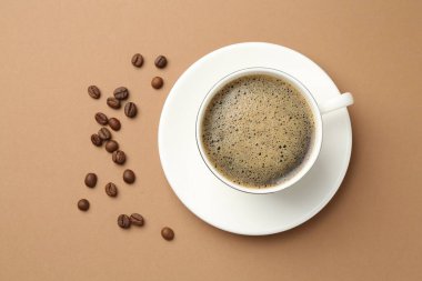 Kahve fincanda, fasulye bej arka planda, düz yerde.