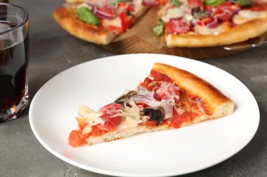 Gri masada servis edilen ince tütsülenmiş sosisli, lezzetli bir pizza.