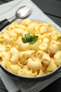 Siyah ahşap masada servis edilen maydanozlu lezzetli makarna ve peynir.