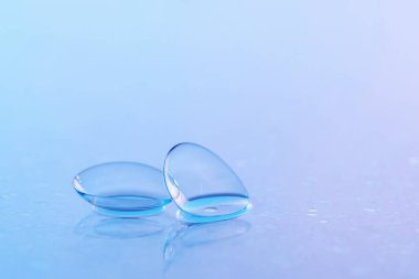 Kontakt lensler ve su damlaları mavi ayna yüzeyine, yakın plan.