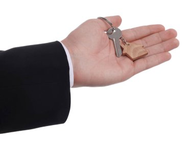 Beyaz arka planda ev anahtarı olan emlakçı, yakın plan.