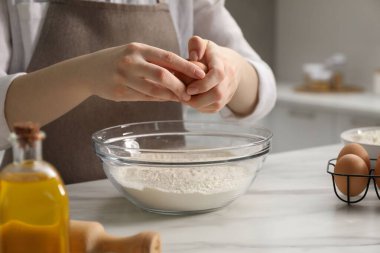 Khinkali yapıyorum. Kadın mutfaktaki masada kaseye yumurta ekliyor, yakın plan.