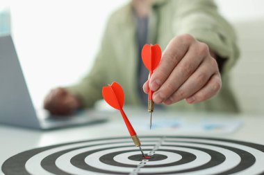 Dart oklu bir adam içeride çalışırken dart tahtasına nişan alıyor, yakın plan.