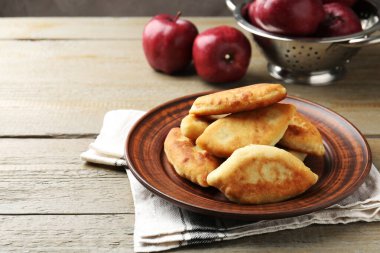 Ahşap masada elmalı lezzetli pirizhky (doldurulmuş turtalar). Metin için boşluk