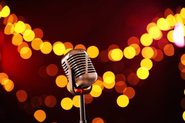 Koyu kırmızı arka planda bulanık ışıkları olan klasik mikrofon. Müzik ekipmanları