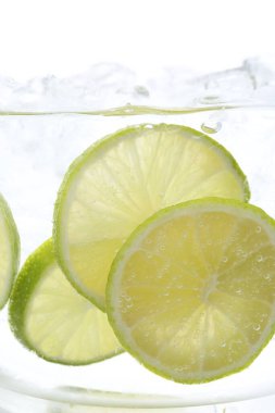 Soda tazeleniyor. Beyaz arka planda limon dilimleri var. Yakın plan.