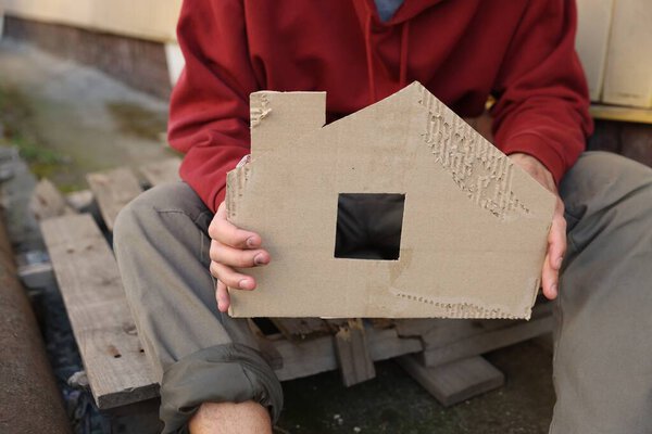 Homeless man with carton house figure outdoors, closeup