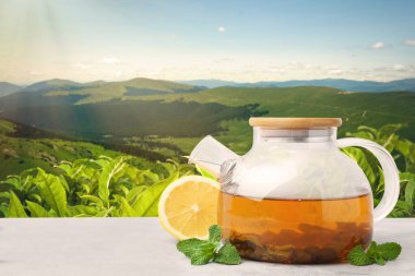 Çaydanlıkta yeşil çay, dağlarda çay tarlasına karşı nane yaprağı ve limon. Metin için boşluk