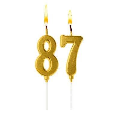 Beyaz arka planda 87 numarayı besteleyen altın renkli mumlar yakıyor. Doğum günü veya diğer özel tarihler için şenlik dekorasyonu